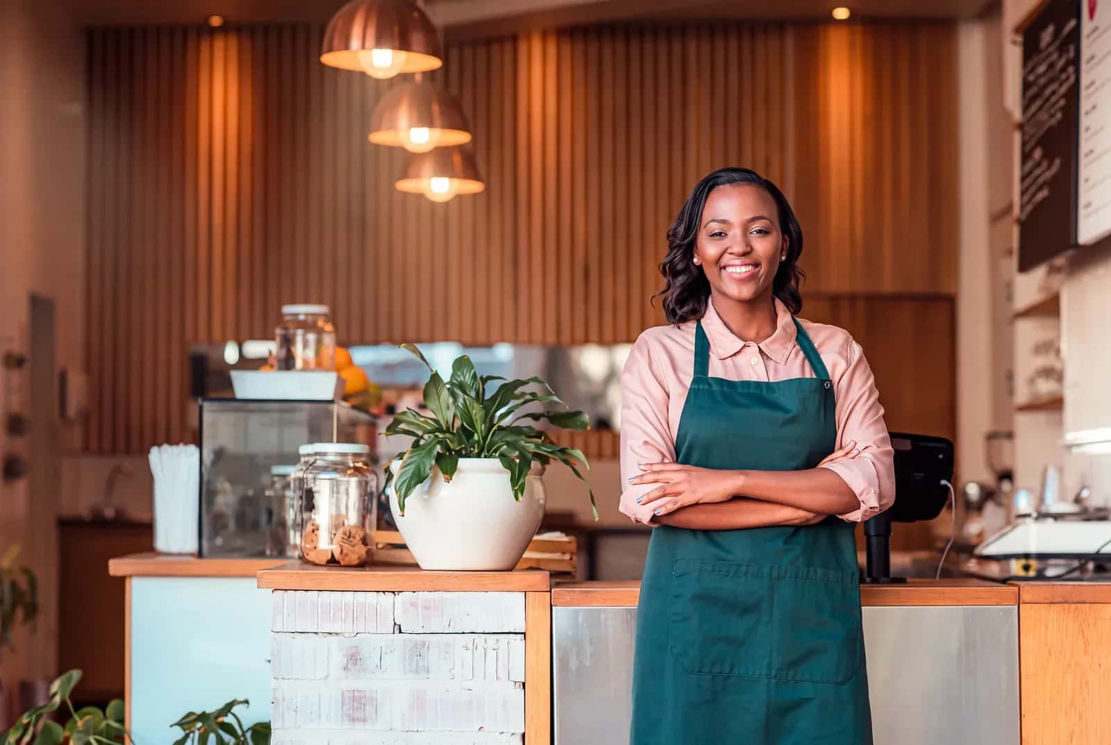 Comerciante sorrindo no balcão do próprio negócio